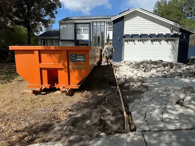 Orange 20-yard Dumpster Strong roll-off placed on a residential driveway during a concrete demo. Photo courtesy of Dumpster Strong.