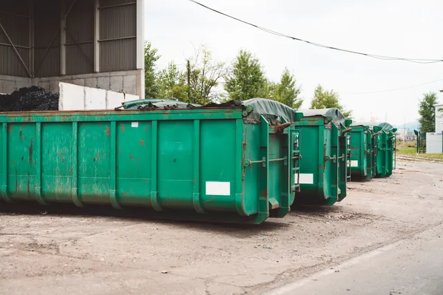 Row of green roll-off containers staged at a transfer station yard. Photo courtesy of Independent Roll-Off Operator.