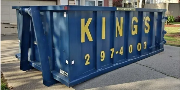 Navy blue King's roll-off container with bold yellow lettering placed in a driveway. Photo courtesy of King's Dumpsters.