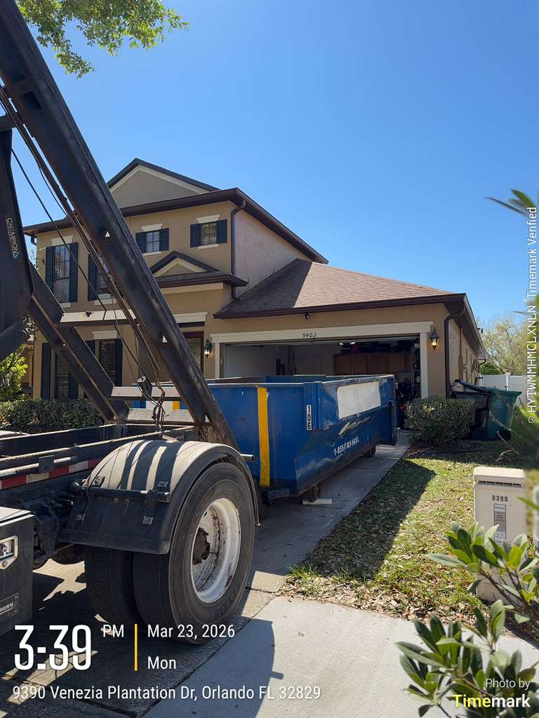 Blue roll-off truck delivering a container to a two-story home in Orlando. Photo courtesy of Metro Roll-Off.